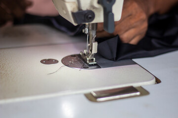A tailor is sewing clothes with a sewing machine.