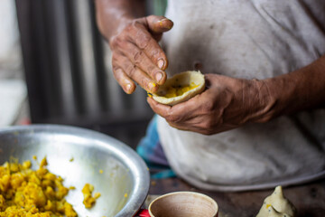 A worker is making a singara in a hotel.