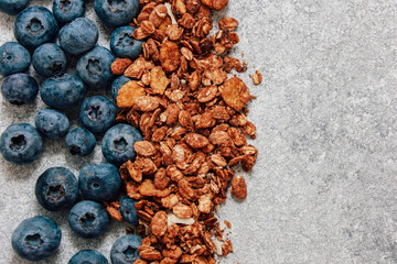 Blueberries and granola arranged on a gray surface for healthy breakfast inspiration