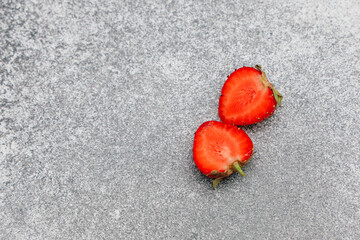 Freshly sliced strawberries on a textured gray surface ready for a healthy snack or dessert