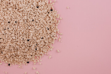 Light-colored granules scattered on a pink background create a textured visual interest in the image