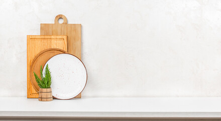 A clean minimalist kitchen display with cutting boards, a ceramic plate, and a rustic herb holder...