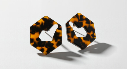 Unique tortoiseshell earrings with an unconventional hexagonal shape on a minimalist background