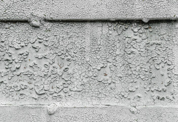 A close-up view of an old wall with cracked, peeling paint and rough textured surface, showing...