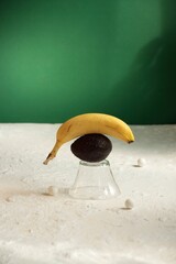 Surreal conceptual still life of a banana balancing on a plum.