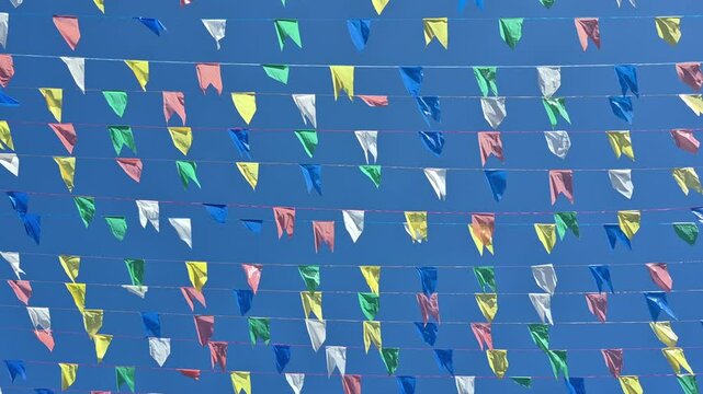 C&eacute;u azul de ver&atilde;o com v&aacute;rias bandeirolas coloridas tremulando presas por fios.