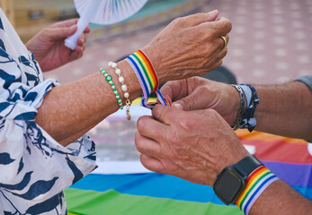 Pareja de gente mayor colocándose pulsera del día del orgullo