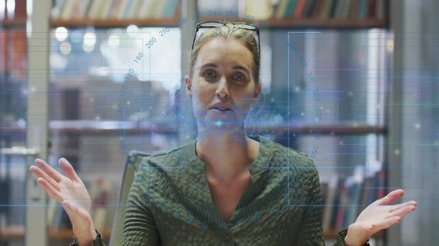 Mid-adult woman at desk activating holographic interface and manipulating controls for tech demo