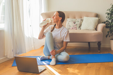 Young woman practicing yoga at home on a sunny day. Serene morning light streaming through the...
