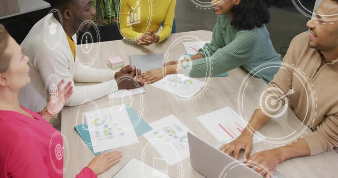 Business colleagues reviewing charts causing animated icons fading exchanging notes before huddling