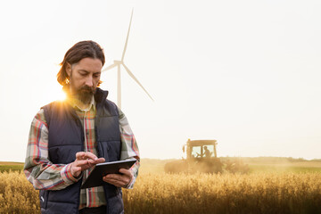 Farmer with a digital tablet on the background of an agricultural tractor