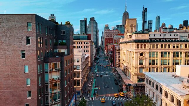 Following multiple yellow cabs in the traffic by the Fifth Avenue. Drone footage along the facades of the buildings in New York City.