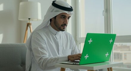 Arab Man Works From Home, Focused on His Green Laptop