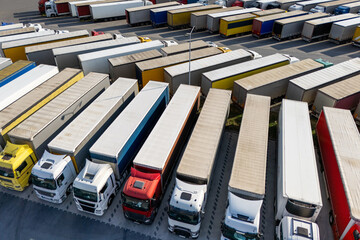 Aerial view of a large truck parking lot at a logistics hub, with multiple commercial semi trucks...