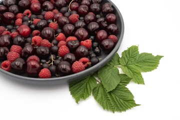 Cherry, raspberry and currant composition on a black plate on a white background - close-up of a...