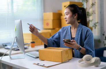 Asian entrepreneur using computer and mobile phone for online selling, startup small business owner working at home office, e-commerce and online shopping concept