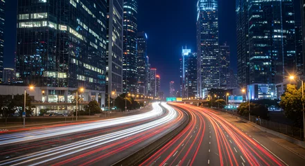 Fotobehang Snelweg bij nacht A view of a busy highway in the middle of a modern city at night, with red and white light trails from fast-moving vehicles, surrounded by brightly lit skyscrapers. This photo depicts the dynamics of   © Laela