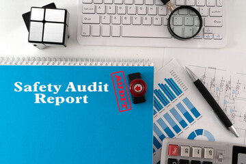A 'Safety Audit Report' document rests on a table, prominently stamped with 'Audit', surrounded by...