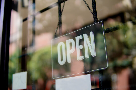 Open sign hanging on glass door of small business shop