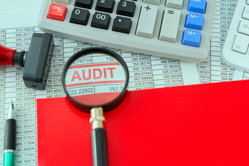 A photo concept for Audit theme; A detailed report is placed under a magnifying glass, symbolizing...