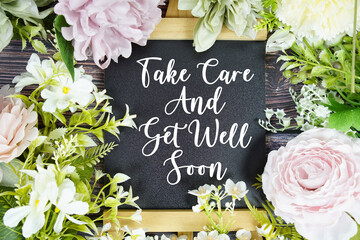 Take care and get well soon text with flowers bouquet decoration on wooden background