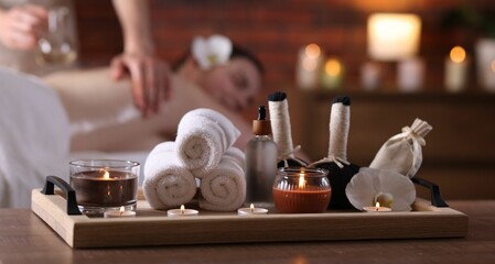 Woman receiving back massage with oil indoors, focus on different spa supplies