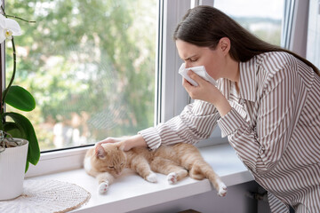 Woman suffering from allergy with her cat near window at home