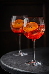 Italian Aperol Spritz cocktail with orange slices on black wooden table. Summer drink, homemade sangria. Copy space