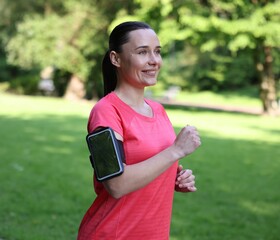 Sporty woman with armband running in park