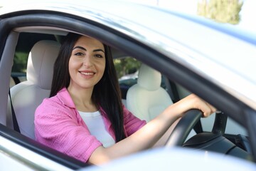 Woman behind steering wheel of modern car, view from outside