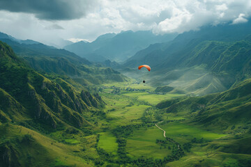 Paraglider soars over lush green valley and majestic mountains under cloudy sky