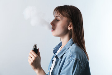 Woman using electronic smoking device on light grey background