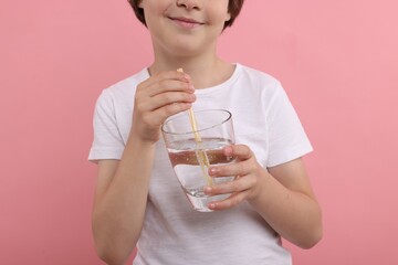 Little boy with glass of refreshing soda drink on pink background, closeup