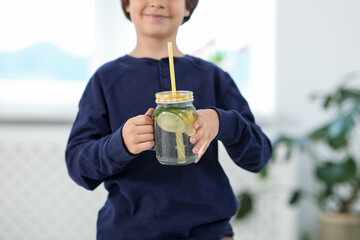 Little boy with mason jar of lemonade at home, selective focus. Refreshing drink