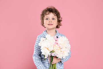 Cute little boy with bouquet of beautiful peonies on pink background