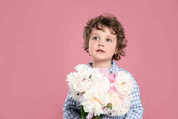 Cute little boy with bouquet of beautiful peonies on pink background. Space for text