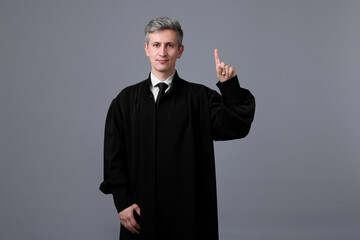 Judge in court dress shaking finger on grey background