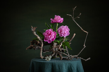 Graceful peonies, radiating elegance and tenderness, with branches and snags. A harmonious combination of the beauty of nature and artistic skill.