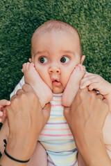 Adorable baby playing with feet on green grass background