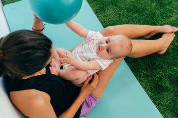 Mother playing with baby and pilates ball on exercise mat