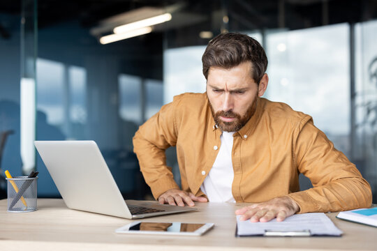 A man experiencing anxiety or a medical emergency at his desk. He looks distressed and concerned