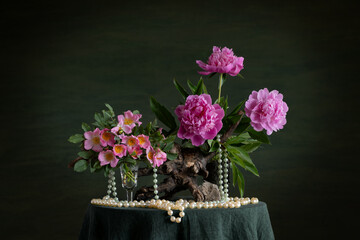 A floral arrangement with a contrast of wild rose thorns and delicate peony petals. Curved branches and driftwood emphasize the harmony between rough textures and delicate floral beauty.