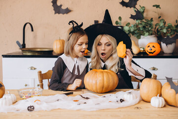 Mother and daughter carving pumpkins for Halloween party