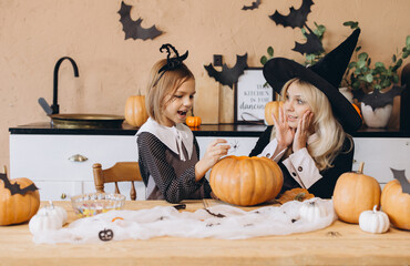 Mother and daughter carving pumpkins and decorating for Halloween