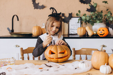 Little girl carving pumpkin face for Halloween party