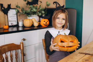 Little Girl Showing Carved Pumpkin Celebrating Halloween at Home