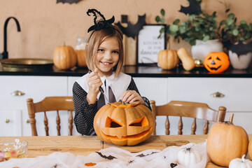 Little girl carving pumpkin for Halloween party at home