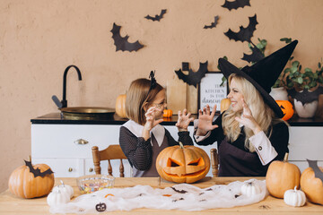Mother and daughter making scary faces, preparing for Halloween party