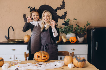 Mother and daughter wearing witch costumes preparing for Halloween party