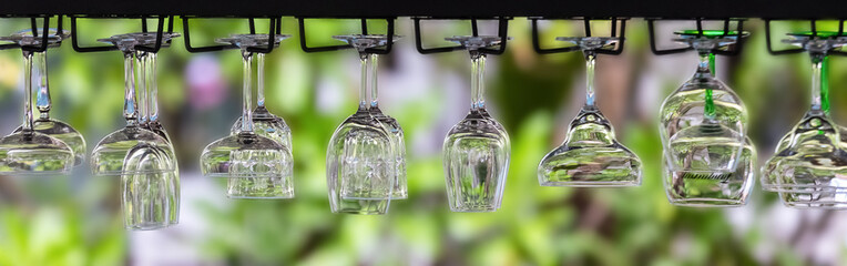 Different types of glasses hanging upside down on a bar
